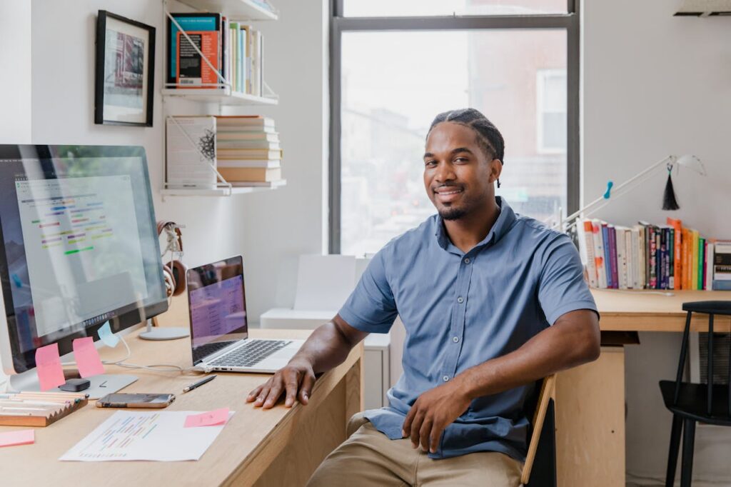 Confident professional man with a welcoming smile sitting at a desk in a contemporary office setting.